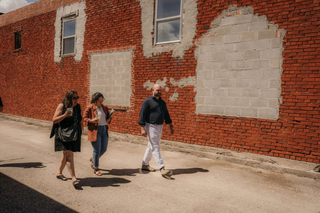 three people walking outside a brick building